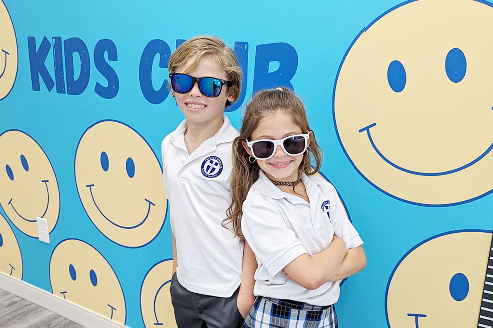 Two young Kids Club members at the smiley wall
