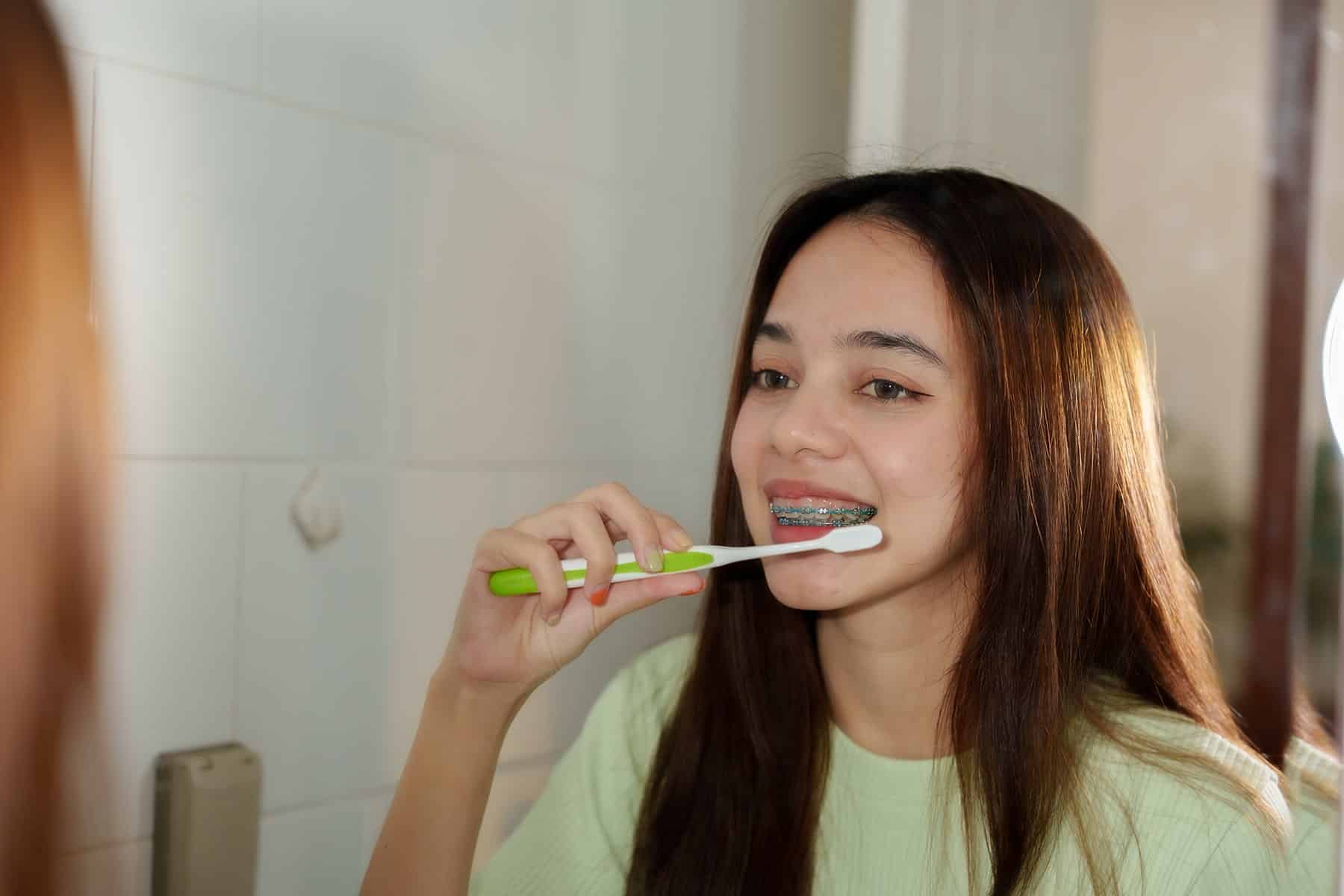 Girl brushing her teeth with braces in Midland, TX